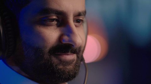 إيماءات الانسجام مع المؤثرات الصوتية والمرئية، استخدام برامج تحرير متطورة لإنتاج الفيديوهات، تصويرمقرب لمونتيرعربي خليجي سعودي يرتدي الثوب الابيض وسماعات الرأس يقوم  بالتأمل والإبداع الفني أمام الشاشة