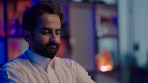 المونتاج الرقمي باستخدام أحدث التقنيات، استخدام برامج تحرير متطورة لإنتاج الفيديوهات، التأمل والإبداع الفني أمام الشاشة، تصوير لمونتيرعربي خليجي سعودي يرتدي الثوب الابيض يقوم بوضع سماعات الرأس