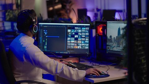 تحرير الفيديو وصناعة المحتوى، التأمل والإبداع الفني أمام الشاشة، تصويرمن الجانب لمونتيرعربي خليجي سعودي يرتدي الثوب الابيض و سماعات الرأس يقوم التفكير العميق والتحليل البصري