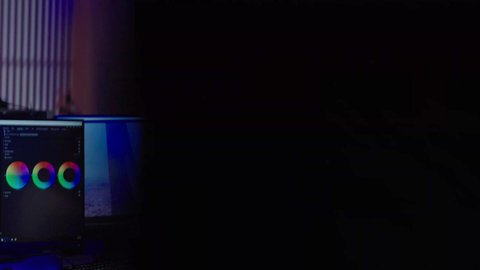 ايماءات الاندماج و التركيز، مفهوم صناعة المحتوى المرئي والإبداع الفني، تصويرمن الخلف لرجل عربي خليجي سعودي  يرتدي الثوب الابيض يضع سماعة الراس يعمل في غرفة المونتاج يستخدم الحاسب المحمول لقص وترتيب المشاهد