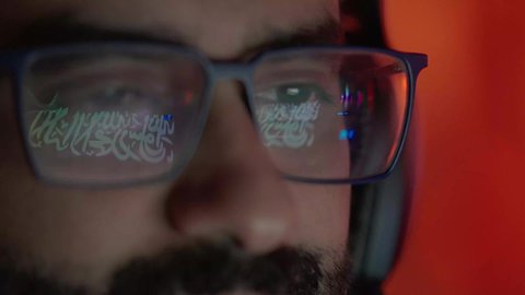 مفهوم الإبداع في صناعة المحتوى السمعي والبصري، ايماءات الاندماج و التركيز، تصوير مقرب لوجه مونتيرعربي خليجي عماني يرتدي الدشداشة و الكمة والنظارة الطبية يركز على شاشة المونتاج