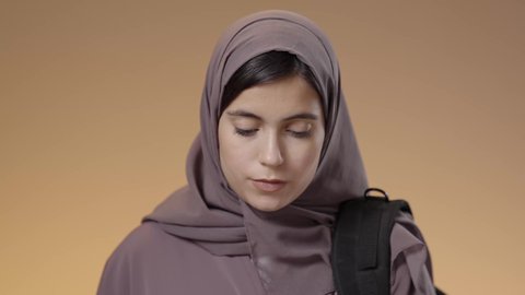 قضاء الوقت بالتعلم والتثقف، الاستعداد للعام الدراسي الجامعي الجديد, بورتريه مقرب لطالبة جامعية عربية سعودية خليجية تحمل الحقيبة الجامعية وتقوم بقراءة كتاب, التشوق للذهاب إلى الجامعه, التعليم في مدارس وجامعات المملكة, المذاكرة والاجتهاد والدراسة، خلفية زرقاء.