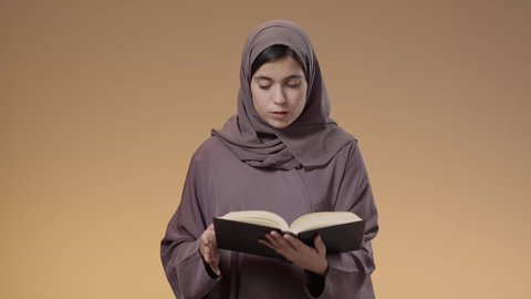 قضاء الوقت بالتعلم والتثقف، الاستمتاع بقراءة الكتب والقصص والروايات، بورتريه لشابة عربية خليجية سعودية محجبة ترتدي العباءة تحمل بيديها كتاب، المذاكرة والاجتهاد والدراسة، ثقافة التعلم الذاتي، خلفية بني