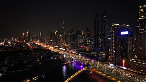 حركة مرور السيارات في الشوارع والطرقات، النمو والتقدم والتوسع العمراني، تصوير درون جوي  للأبراج وناطحات السحاب المضيئة ليلا في مدينة دبي، الفن الهندسي المعماري للمباني والمنشآت في الإمارات العربية المتحدة