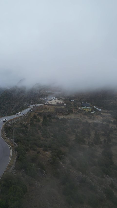 سلاسل جبال أبها والنماص الصخرية، التضاريس والطرق الحجرية الوعرة، تصوير جوي للبيئة الجبلية في منطقة عسير، السحب البيضاء والجو الضبابي المغطي للقمم العالية، الطبيعة الخضراء والمنتزهات والحدائق الجميلة، الأشجار والنباتات على سفوح الجبل