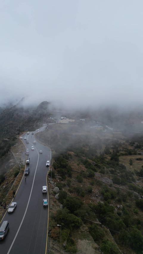 سلاسل جبال أبها والنماص الصخرية، التضاريس والطرق الحجرية الوعرة، تصوير جوي للبيئة الجبلية في منطقة عسير، السحب البيضاء والجو الضبابي المغطي للقمم العالية، الطبيعة الخضراء والمنتزهات والحدائق الجميلة، الأشجار والنباتات على سفوح الجبل