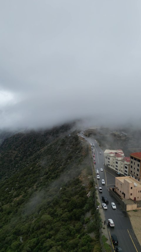 سلاسل جبال أبها والنماص الصخرية، التضاريس والطرق الحجرية الوعرة، تصوير جوي للبيئة الجبلية في منطقة عسير، السحب البيضاء والجو الضبابي المغطي للقمم العالية، الطبيعة الخضراء والمنتزهات والحدائق الجميلة، الأشجار والنباتات على سفوح الجبل