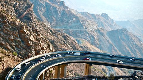 حركة سير السيارات على ممر جبلي ملتوي، المناطق الطبيعية والمعالم التاريخية السياحية في مكة، تصوير درون لطريق عقبة الهدا في مدينة الطائف، الأجواء الضبابية والطبيعة الصحراوية والمرتفعات الجبلية في المملكة العربية السعودية