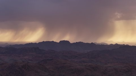 هطول الامطار فوق الجبال والتكوينات الصخرية في المناطق الصحراوية في المملكة العربية السعودية، مكان أثري تاريخي قديم، التضاريس والقمم والمرتفعات الجبلية في الصحراء، فصل الشتاء في مدينة حائل