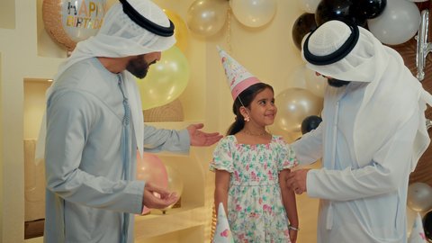 زينة عيد الميلاد، التعبير عن المحبة والألفة بين الاهل، ايماءات وجه تدل على الإستمتاع والفرح، الزيارات العائلية وتجمعات الأسر، تصوير مقرب لعائله عربيه خليجيه اماراتية ترتدي الثوب التقليدي تحتفل بعيد الميلاد مع  طفتلهم