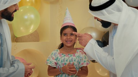 التعبير عن المحبة والألفة بين الاهل، ايماءات وجه تدل على الإستمتاع والفرح، الزيارات العائلية وتجمعات الأسر، زينة ومفرقعات الحفلات، تصوير مقرب لعائله عربيه خليجيه اماراتية ترتدي الثوب التقليدي تحتفل بعيد الميلاد مع  طفتلهم