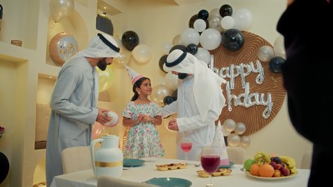 ايماءات وجه تدل على الإستمتاع والفرح، الزيارات العائلية وتجمعات الأسر، زينة ومفرقعات الحفلات، عائله عربيه خليجيه اماراتية ترتدي الثوب التقليدي تحتفل بعيد الميلاد مع  طفتلهم