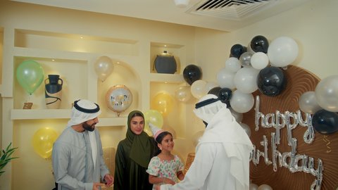 مفاجآت وأعياد ومناسبات ، أجواء لمة الأهل في المناسبات والاحتفالات السعيدة ، زينة ومفرقعات الحفلات، عائله عربيه خليجيه اماراتية ترتدي الثوب التقليدي تحتفل بعيد الميلاد مع  طفتلهم ،ايماءات وجه تدل على الإستمتاع والفرح، اب خليجي يقوم بالرقص مع ابنته