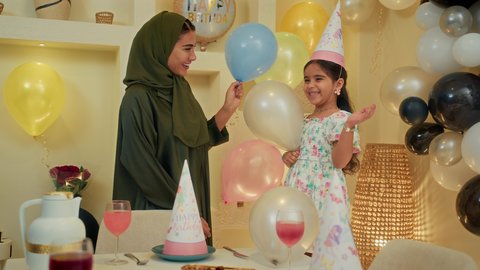 أعياد ومناسبات وأجواء احتفالية عائلية سعيدة، زينة ومفرقعات الحفلات،ام  عربية اماراتية خليجية تحتفل بعيد الميلاد مع طفلتها،ايماءات وجه تدل على الإستمتاع والفرح