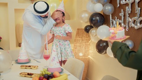 ايماءات المفجاءة و الاندهاش، اعياد ومناسبات سعيدة، مشاركة لأجواء رائعة عائلية داخل المنزل، ام عربية خليجيه تقوم بتقديم كعكة يوم الميلاد المزينة بالشموع، عائله عربيه خليجيه اماراتية تقوم بالاحتفال بعيد ميلاد ابنتهم