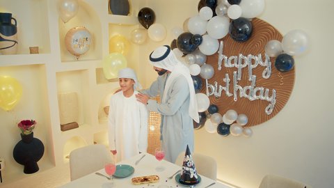 التهنئة بالأعياد والمناسبات السعيدة  ، زينة أعياد الميلاد، عائله عربيه خليجيه اماراتية تقوم بالاحتفال بعيد الميلاد  ، رجل عربي خليجي اماراتي يرتدي الزي التقليدي يقوم بتقبيل الولد ، ايماءات السعادة و السرور