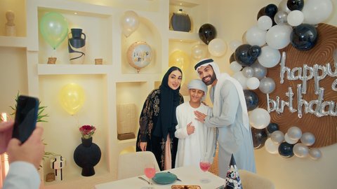 استخدام الأجهزة التقنية المتطورة، توثيق اللحظات السعيدة، زينة أعياد الميلاد و المناسبات، ،عائله عربيه خليجيه اماراتية تقوم بالاحتفال بعيد ميلاد ابنهم ،تصوير مقرب ليد رجل عربي خليجي يقوم بالتقاط صورة تذكارية ، ايماءات السعادة و السرور