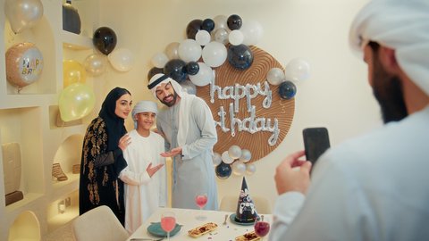 توثيق اللحظات السعيدة، استخدام الأجهزة التقنية المتطورة،  زينة أعياد الميلاد و المناسبات، ،عائله عربيه خليجيه اماراتية تقوم بالاحتفال بولدهم ، رجل عربي خليجي يقوم بالتقاط صورة تذكارية ، ايماءات السعادة و السرور