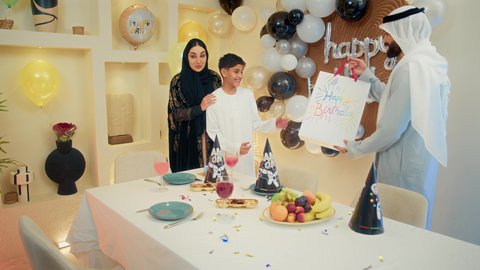 مناسبات وأعياد سعيدة، تعزيز الروابط العائلية والمحبة والمودة بين الأسرة، عائلة عربية خليجية إماراتية تقوم بالاحتفال و تقديم الهدايا، إيماءات الفرح و السعادة، مشاعر الحب والحنان في اجتماع عائلي سعيد