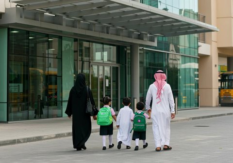 Back view of a Saudi Arabian Gulf father and mother with their children going to school, interest in science and education, start of school, new year and bright Saudi future, modern and advanced schools in the Kingdom of Saudi Arabia