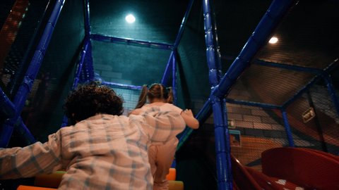 مركز العاب ترفيهي داخلي ، أجواء حيوية ومبهجة، قضاء اوقات سعيدة ، تصوير لطفلان عربيان خليجيان إماراتيان برتديان الزى الكاجوال ، يستمتعان بالانزلاق على زحليقة كبيرة ، الأنشطة الرياضية الممتعة