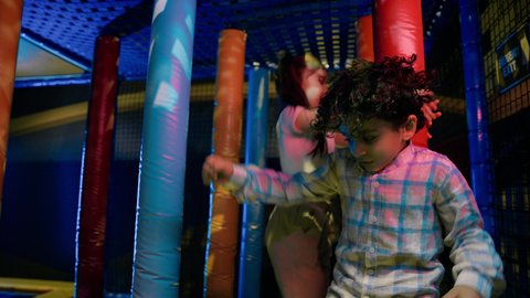 القفز بداخل مركز العاب داخلي ،  تصوير لطفلان عربيان خليجيان إماراتيان برتديان الزى الكاجوال ،  يتجاوزان العوائق المطاطية ، يستكشفان المسارات المليئة بالتحديات، الأنشطة الرياضية الممتعة ، قضاء اوقات سعيدة