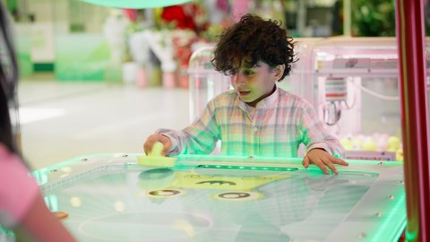 منافسة مليئة بالتحدي والإثارة ،ايماءات الاندماج والتفاعل ، قضاء الاوقات السعيدة مع العائلة، الأنشطة الرياضية الممتعة ، تصوير لطفلان اشقاء عربيان خليجيان إماراتيان يرتديان الزى الكاجوال ، يستمتعان بلعبة الهوكي الهوائي