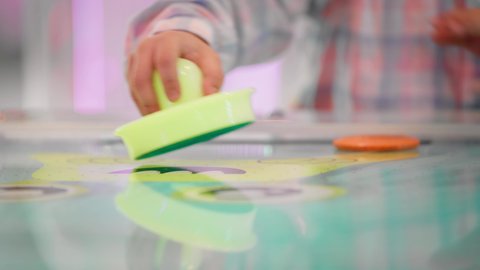 قضاء الاوقات السعيدة ،ايماءات الاندماج والتفاعل ، منافسة مليئة بالتحدي والإثارة ، الأنشطة الرياضية الممتعة ، تصوير لطفل عربي خليجي إماراتي يرتدي الزى الكاجوال ، يستمتع بلعبة الهوكي الهوائي