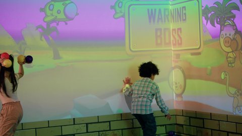 أجواء المرح والحماس ، الأنشطة الرياضية الممتعة، منافسة مليئة بالتحدي والإثارة ، التفاعل بين أفراد العائلة ، تصوير لطفلان اشقاء عربيان خليجيان إماراتيان يرتديان الزى الكاجوال ، يستمتعان بلعبة الرمي التفاعلية