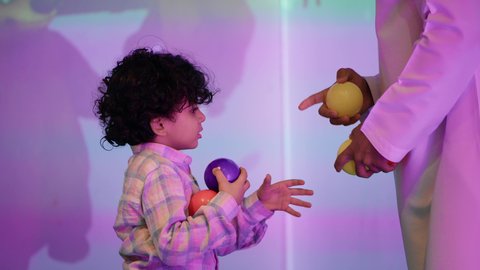 الاستمتاع بلحظات المرح والحماس ، أجواء تفاعلية مبهجة ، مركز ألعاب ترفيهي، تعابير السرور والسعادة،  قضاء الاوقات السعيده مع الابناء ، تصوير لعائلة عربية خليجية إماراتية تستمتع بوقت ممتع في لعبة الرمي التفاعلية