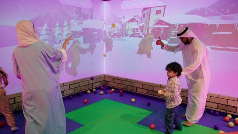 قضاء الاوقات السعيده مع الابناء ، أجواء تفاعلية مبهجة ،تصوير لعائلة عربية خليجية إماراتية تستمتع بوقت ممتع في لعبة الرمي التفاعلية ، مركز ألعاب ترفيهي، مشاركة الأب والأم أطفالهما لحظات المرح والحماس ، تعابير السرور والسعادة