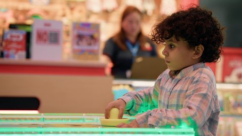 تعابير الهزيمة والخسارة، مراكز الالعاب الترفيهيه في الامارات، تصوير لطفل عربي خليجي إماراتي يرتدي الزى الكاجوال ، يلعب لعبة الهوكي الهوائي  ، طاولة مضيئة بألوان زاهية