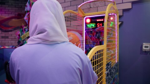 تعزيز المهارات الذهنية عند الابناء، المتعة في مراكز الالعاب الترفيهيه في الامارات، دمج التقنيات الحديثه فى ألعاب الاطفال، تصوير من الخلف للسيدة عربية خليجية اماراتية محجبة ترتدي العباءة تقوم بمشاركة ابنتها لعبة رمي كرة السلة، قضاء وقت ممتع باللعب والتركيز