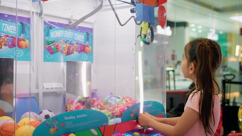 الشعور بالمتعة والفرح، بنت سعودية تقضي وقت ممتع في المراكز الترفيهية في الامارات، التركيز والقدرة على التحكم، صالات ألعاب الأركيد المتطورة، تصوير من الجانب لفتاة عربية خليجية اماراتية ترتدي الزي الكاجوال تلعب آلة مخلب الالتقاط الالكترونية، قسم التحديات والمغامرات.