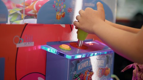 صالات ألعاب الأركيد المتطورة، قسم التحديات والمغامرات، التركيز والقدرة على التحكم، الشعور بالمتعة والفرح، بنت سعودية تقضي وقت ممتع في المراكز الترفيهية في الامارات، تصوير مقرب لأيدي فتاة عربية خليجية اماراتية تلعب آلة مخلب الالتقاط الالكترونية.