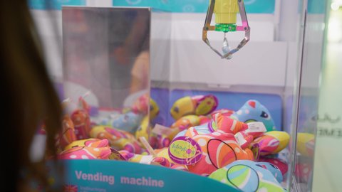 الفرح والسرور بالفوز والانتصار، صالات ألعاب الأركيد المتطورة، قسم التحديات والمغامرات، التركيز والقدرة على التحكم، بنت سعودية تقضي وقت ممتع في المراكز الترفيهية في الامارات، تصوير مقرب لفتاة عربية خليجية اماراتية تلعب آلة مخلب الالتقاط الالكترونية.