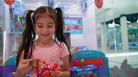 المراكز الترفيهية في الامارات، الفوز بلعبة آلة مخلب الالتقاط الالكترونية، قسم التحديات والمغامرات، بنت سعودية تقضي وقت ممتع في صالات ألعاب الأركيد المتطورة، تصوير مقرب لفتاة عربية خليجية اماراتية ترتدي الزي الكاجوال تمسك لعبتها بتعابير السرور والسعادة