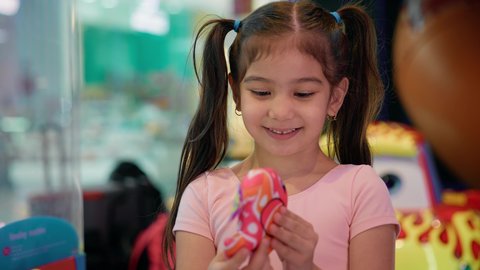 الانتصار والفوز بلعبة آلة مخلب الالتقاط الالكترونية، صالات ألعاب الأركيد المتطورة، قسم التحديات والمغامرات، بنت سعودية تقضي وقت ممتع في المراكز الترفيهية في الامارات، تصوير مقرب لفتاة عربية خليجية اماراتية ترتدي الزي الكاجوال تمسك لعبتها بتعابير السرور والسعادة