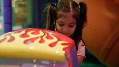 أجواء تفاعلية مبهجة، المتعة والتسلية في المراكز الترفيهية في الامارات، الشعور بالحماس والفرح، تصوير مقرب لفتاة عربية خليجية اماراتية ترتدي الزي الكاجوال تمسك مقود سيارة الأطفال الكهربائية، التركيز والقدرة على التحكم .