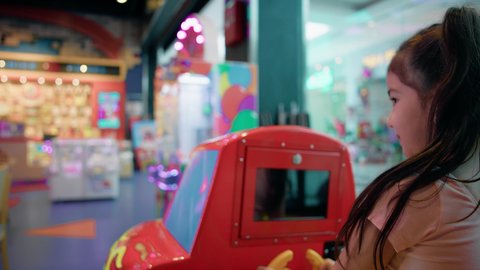 الشعور بالحماس والفرح، صالات الألعاب المتطورة، أجواء تفاعلية مبهجة، المتعة والتسلية في المراكز الترفيهية في الامارات،فتاة عربية خليجية اماراتية ترتدي الزي الكاجوال تمسك مقود لعبة سيارة الأطفال الكهربائية، التركيز والقدرة على التحكم .