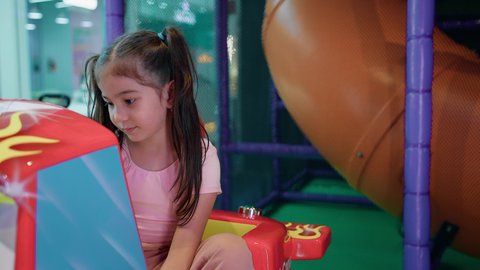 الشعور بالحماس والفرح، صالات الألعاب المتطورة، أجواء تفاعلية مبهجة، المتعة والتسلية في المراكز الترفيهية في الامارات،فتاة عربية خليجية اماراتية ترتدي الزي الكاجوال تمسك مقود لعبة سيارة الأطفال الكهربائية، التركيز والقدرة على التحكم .