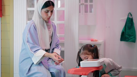 أم إماراتية ترتدي عباءة تقوم باللعب مع ابنتها، فتاة عربية خليجية سعودية ترتدي الزي الطبي تقوم بمعالجة يد والدتها، الاستمتاع في مركز الالعاب الترفيهي، مفهوم التعليم عن طريق اللعب، تعريف الأطفال على المهن المستقبلية، تعلم الاسعافات الاولية