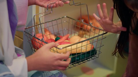 دعم وتنمية مهارات الأطفال، تعليم الابناء تسوق الخضار الطازجة من قسم البقالة، قضاء وقت ممتع في مركز الالعاب الترفيهيه، فتاة عربية خليجية سعودية ترتدي مئرز الطبخ، تصوير مقرب لسيدة عربية خليجية إماراتية محجبة تقوم بمشاركة ابنتها لحظات المرح، طعام صحي ومفيد