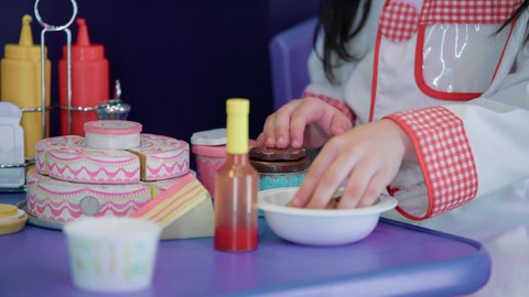 شغف البنات في المطبخ والطهي، الاستمتاع في اللعب في مركز الالعاب الترفيهيه، تنمية مهارات الطبخ عند الأطفال، تعابير السعادة والسرور، تصوير مقرب لفتاة عربية خليجية إماراتية ترتدي زي الشيف الخاص تقف أمام طاولة عليها مجموعة من ادوات الطبخ، مهن ووظائف مستقبلية