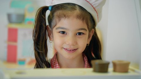 النظر إلى الكاميرا بإيماءات السرور، مهن ووظائف مستقبلية، دعم وتنمية مهارات الطبخ عند الأطفال، شغف البنات في المطبخ والطهي، الاستمتاع في اللعب في مركز الالعاب الترفيهيه، تصوير مقرب لفتاة عربية خليجية إماراتية ترتدي زي الشيف الخاص