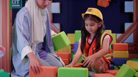 الاهتمام بالأبناء ودعمهم، مراكز الالعاب الترفيهيه في الامارات، تعزيز المهارات الذهنية والفكرية،  قضاء أوقات ممتعة باللعب والتركيز، طفلة عربية خليجية إماراتية ترتدي الزى الكاجوال، ام عربية خليجية سعودية تقوم بتركيب المكعبات مع ابنتها، رعاية وتطوير مهارات الأطفال