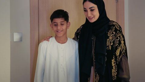 المودة و الانسجام والالفة بين افراد الاسرة، مفهوم التربيه القائمه على الحب والحنان، أم عربيه خليجيه اماراتية ترتدي العباءة تدخل غرفه النوم برفقه ولدها ، ايماءات السعادة و السرور ،  قضاء وقت ممتع مع الاولاد