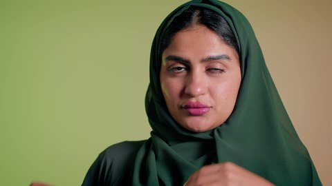 ارتداء عباءة ملونة عصرية، الإهتمام بالموضة والجمال والأناقة، تصوير مقرب لإمرأة عربية سعودية خليجية تنظر إلى الكاميرا بإيماءات الثقة بالنفس، ترتيب الحجاب والاستعداد للذهاب، عرض الملابس والاكسسوارات النسائية السعودية، خلفية ملونة