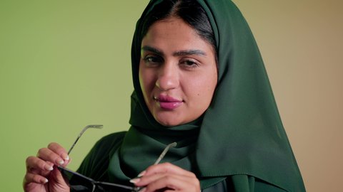 عرض احدث موديلات النظارات الشمسية، متابعة آخر صيحات الموضة, تصوير مقرب لإمرأة عربية خليجية سعودية مبتسمة ترتدي الحجاب والعباءة تقوم بوضع النظارة، الأناقة والاهتمام بالمظهر الخارجي، سيدة اماراتية تقوم بالعروض الإعلانية التسويقية للمنتجات المحلية، خلفية ملونة
