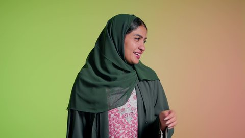 تبادل النظارة بين الصديقات، الاهتمام بالمظهر الخارجي والاناقة الشخصية، سيدة اماراتية تقوم بعرض احدث موديلات النظارات الشمسية، تصوير مقرب لإمرأة عربية خليجية سعودية مبتسمة ترتدي الحجاب والعباءة تقوم بالتسويق للمنتجات المحلية، خلفية ملونة